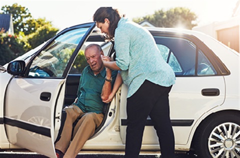 woman helps older person out of car