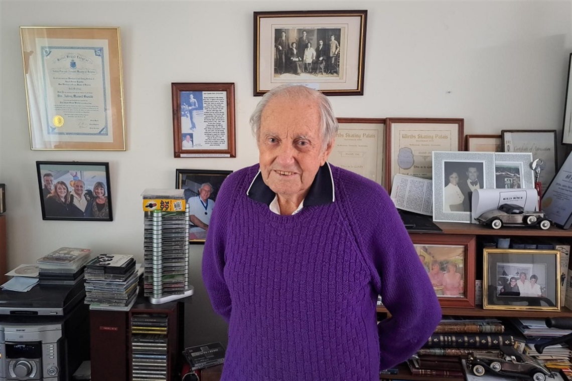 Aubrey stands in front of a wall of family photos and life memorabilia.