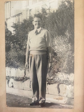 An old black and white photo of Lorraine's father, where he is standing and smiling at the camera.