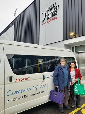 Two AccessCare clients stand together in front of the AccessCare community bus, which is parked in front of the Danny Frawley Centre.