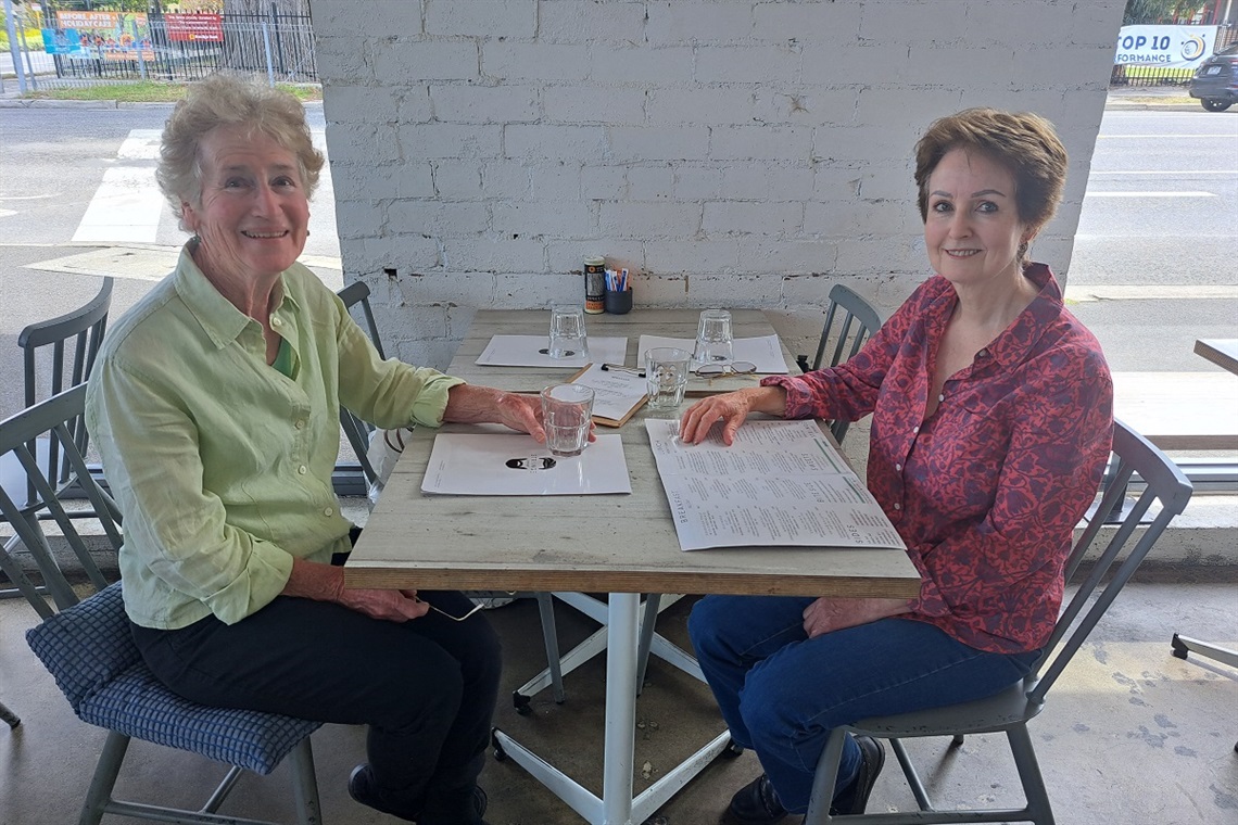 An AccessCare client and a volunteer enjoy a coffee together at a cafe.