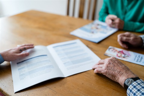 AccessCare brochures are open on a dining table with prospective clients looking over them