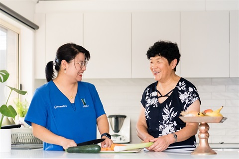 An AccessCare support worker helps a client to prep a meal in their kitchen.