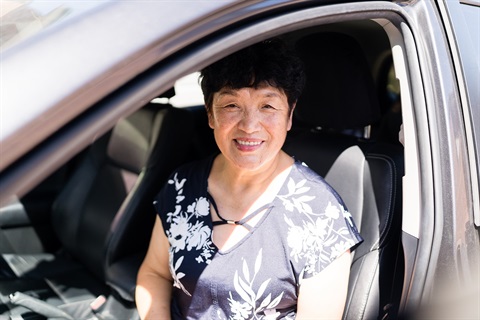 An AccessCare client sits in the passenger side seat of a support worker's car.