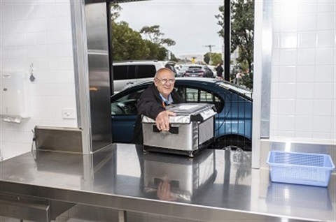 An AccessCare meal delivery volunteer picks up a meal delivery box from the AccessCare kitchen.